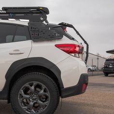 the back end of a white car with luggage strapped to it's roof rack