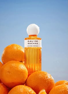 an orange with a white top sitting in front of some oranges and a bottle