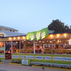 the outside of a restaurant with people sitting at tables and standing in front of it