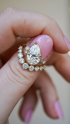 a woman's hand holding an engagement ring with three diamonds on the top and bottom