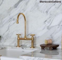 a bathroom with marble counter tops and gold faucets