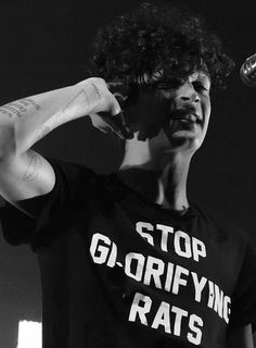 a man with tattoos on his arm holding a microphone and wearing a t - shirt that says stop g - grififying rats