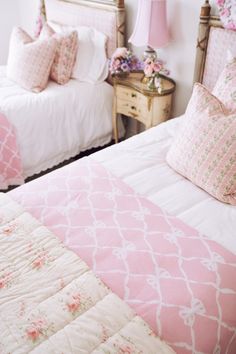 two beds in a bedroom with pink and white bedding