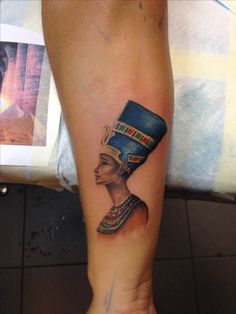 an egyptian woman's leg with a tattoo on her left arm and headdress