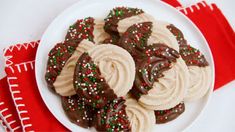 chocolate covered cookies with sprinkles on a plate next to a red and white napkin