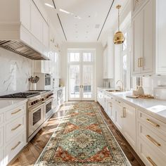 a large rug in the middle of a kitchen with white cabinets and gold trimmings