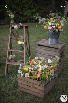 two wooden planters with flowers in them on the grass next to an old ladder