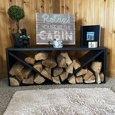 a pile of firewood sitting on top of a rug next to a wooden wall