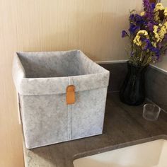 a white sink sitting next to a black vase filled with flowers