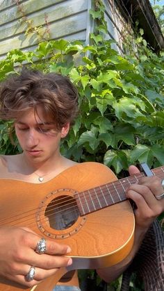 a young man holding an acoustic guitar in his hands