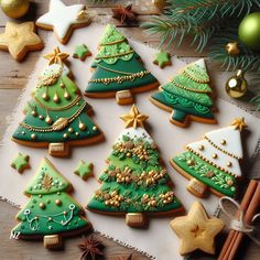 christmas cookies decorated with green and gold trees on a table next to cinnamon sticks, star decorations and ornaments