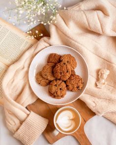 chocolate chip cookies on a plate next to a cup of coffee and an open book