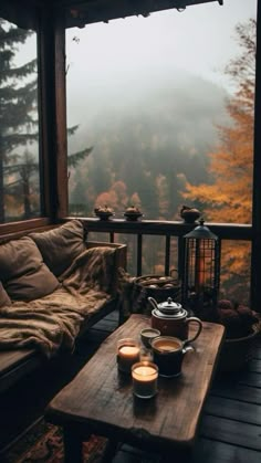 two cups of coffee sit on a wooden table in front of a window overlooking the mountains