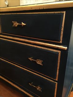 a black dresser with gold trim and arrows on it