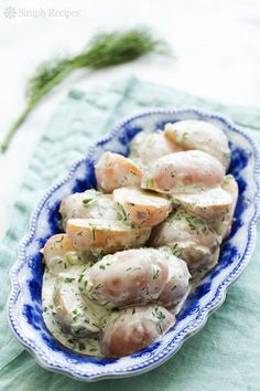 a blue and white bowl filled with potatoes covered in gravy on top of a green table cloth