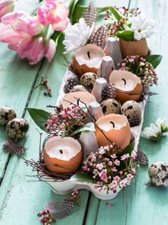 an arrangement of eggs and flowers on a table