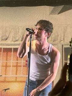 a man standing in front of a microphone on stage