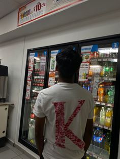 a man standing in front of a refrigerator filled with drinks and sodas at a convenience store