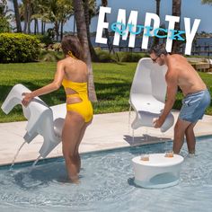 two people in swimsuits playing with an empty chair next to a swimming pool