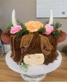 a cake decorated to look like a cow with flowers on it's head is sitting on a table