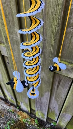 a crocheted yellow and blue garland hanging from a wooden fence