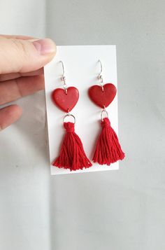 a pair of red heart shaped earrings with tassels hanging from the end of them