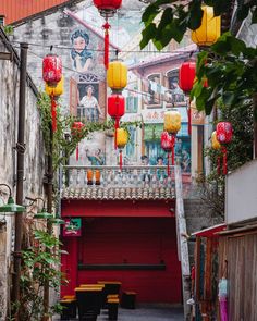 an alleyway with chinese lanterns hanging from the ceiling and benches on the sidewalk below