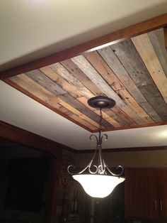 a chandelier hanging from the ceiling in a room with wood paneling on it