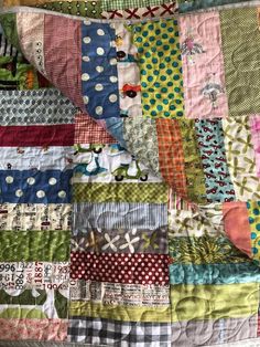 a colorful quilt is laying on top of a tablecloth with polka dots and flowers