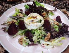 a white plate topped with lettuce and beets next to other food items