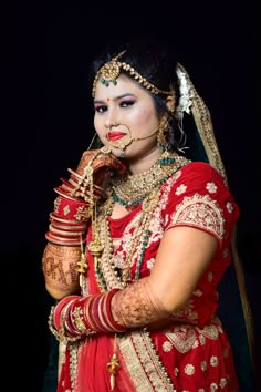 a woman dressed in red and gold poses for the camera with her hands on her face