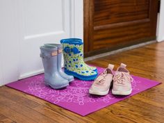 two pairs of rubber boots sitting on top of a mat next to a pair of rubber boots