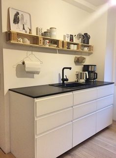 a kitchen with white cabinets and black counter top next to a wall mounted coffee maker