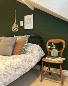 a bedroom with green walls and a bed covered in blankets, pillows and throw pillows