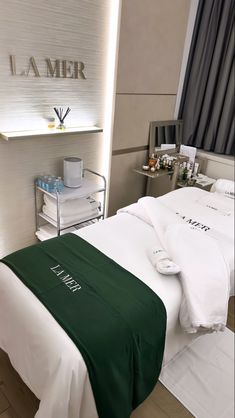 a bed with white sheets and green bedspread in a room that says la mer