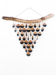 a wooden wind chime hanging from a tree branch with black and brown circles on it