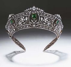 a tiara with emeralds and diamonds on the headband is seen in this image