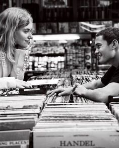 a man and woman are looking at records in a record store