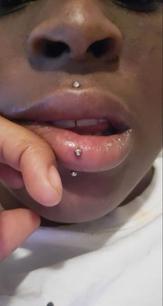 a close up of a person with piercings on their nose and fingers in front of her face