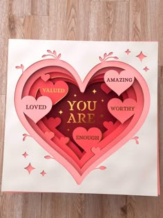 a valentine card with the words you are loved and two hearts cut out of paper