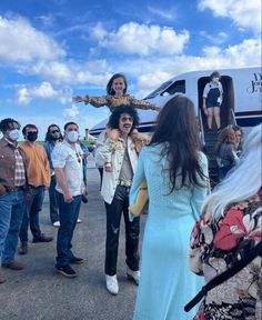 a group of people standing in front of an airplane on the tarmac, with one person wearing a costume