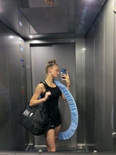 a woman is taking a selfie in an elevator with her cell phone and bag