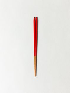 two red chopsticks on a white surface