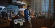 a man standing in the middle of a kitchen next to an oven and stove top