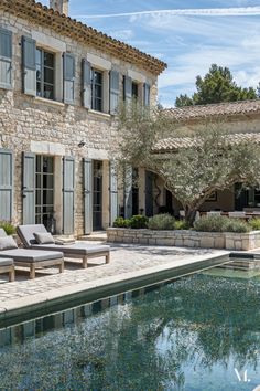 an outdoor swimming pool with chaise lounges next to it and stone buildings in the background