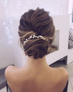 the back of a woman's head with hair in a low bun and pearls on it