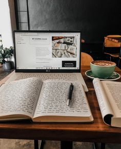 an open book sitting on top of a laptop computer next to a cup of coffee