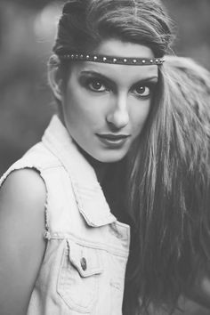 a woman with long hair wearing a headband and looking at the camera, in black and white