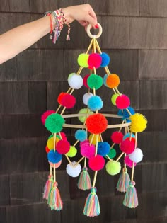 a hand holding a multicolored mobile with pom - poms