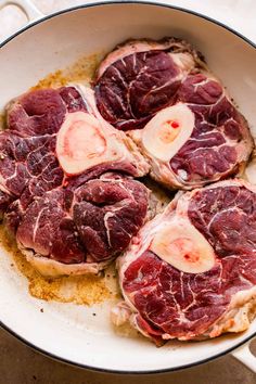 three pieces of meat in a skillet on a counter top with seasoning sprinkled around them